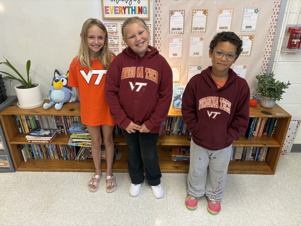 Three smiling elementary students showing off their Virginia Tech colors and shirts