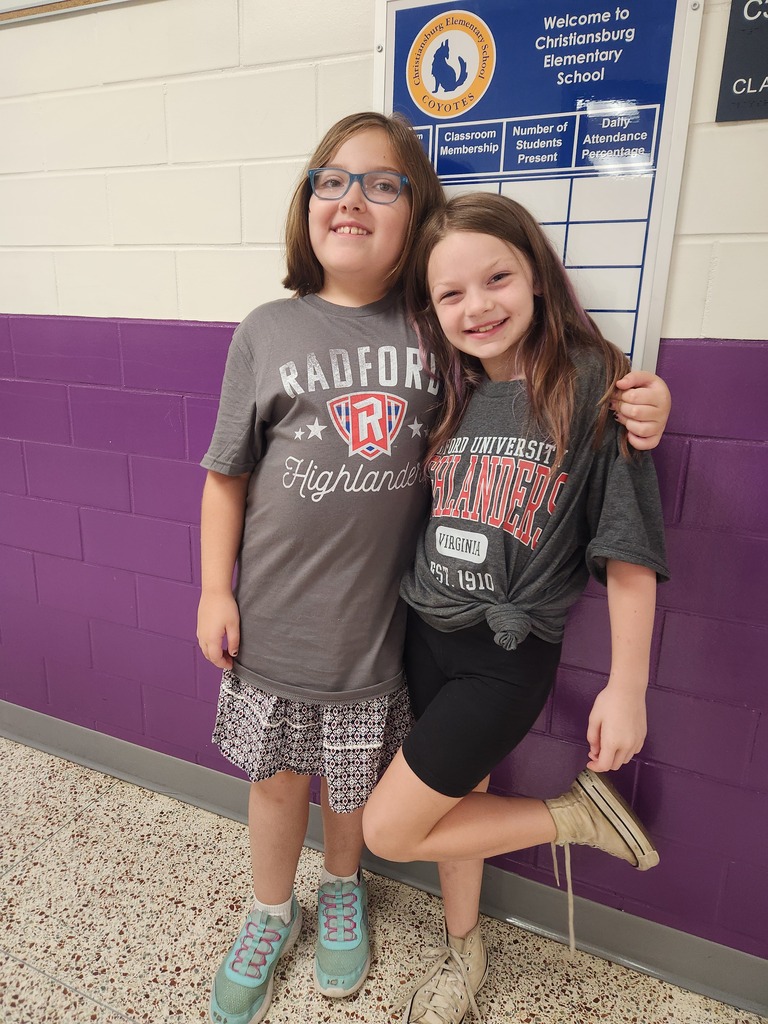 Two elementary students smiling and showing pride in thier Radford University tee shirts