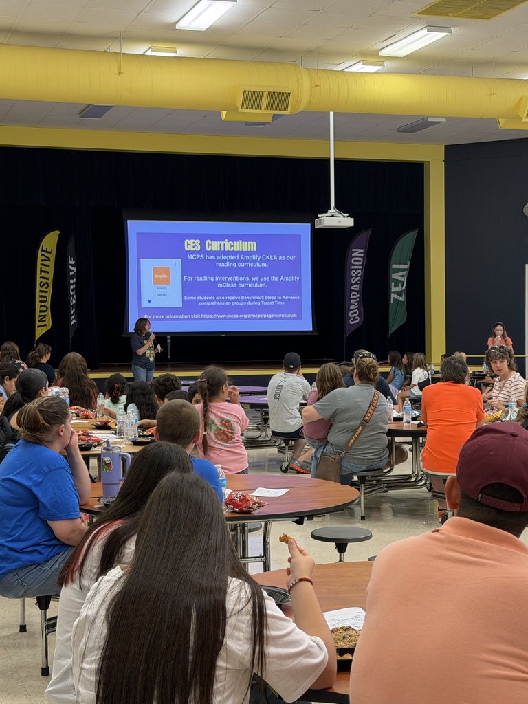 Families gather in the CES cafeteria during Title I Literacy Night while a staff member presents information about the school’s reading curriculum on a large screen.