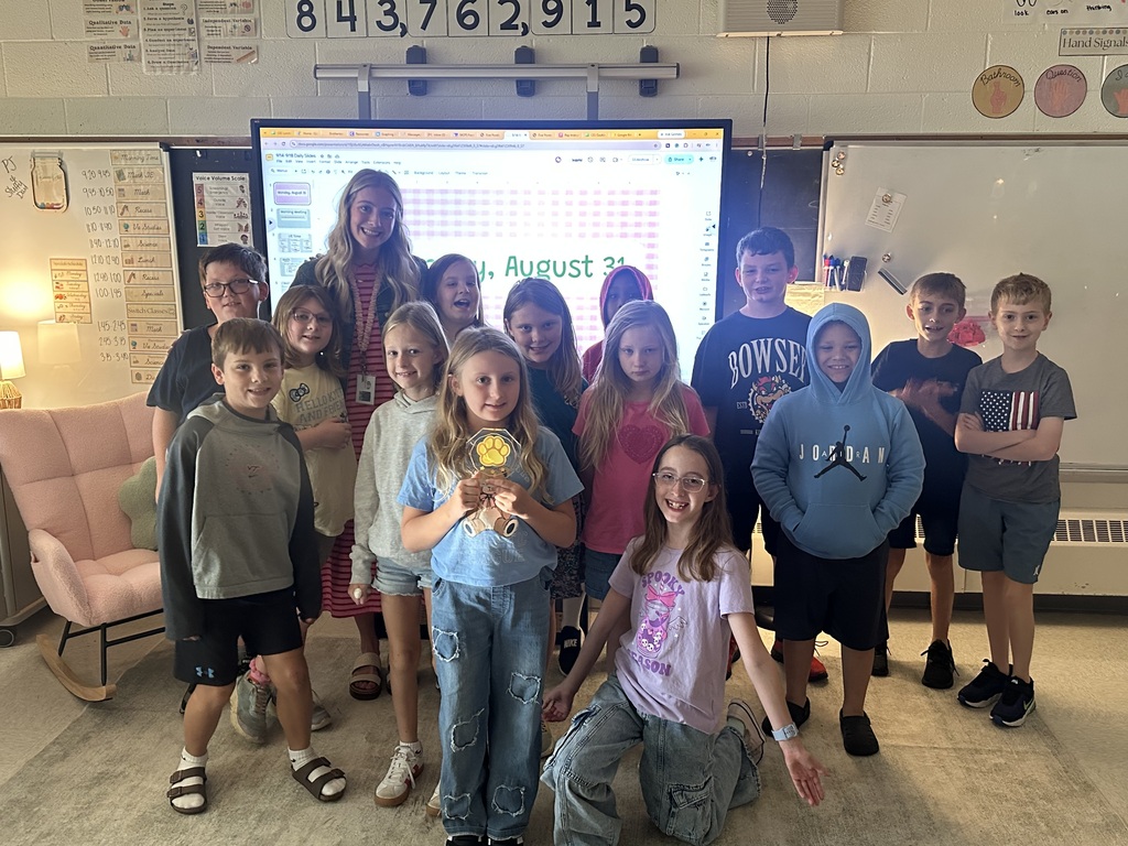 Group of elementary students in a soft toned room smiling because they won a prize.