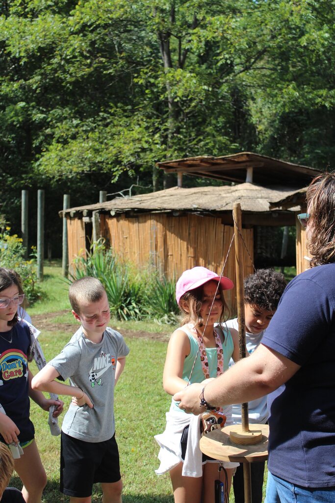 Students learning about native american culture outside  hut at a native american museum.