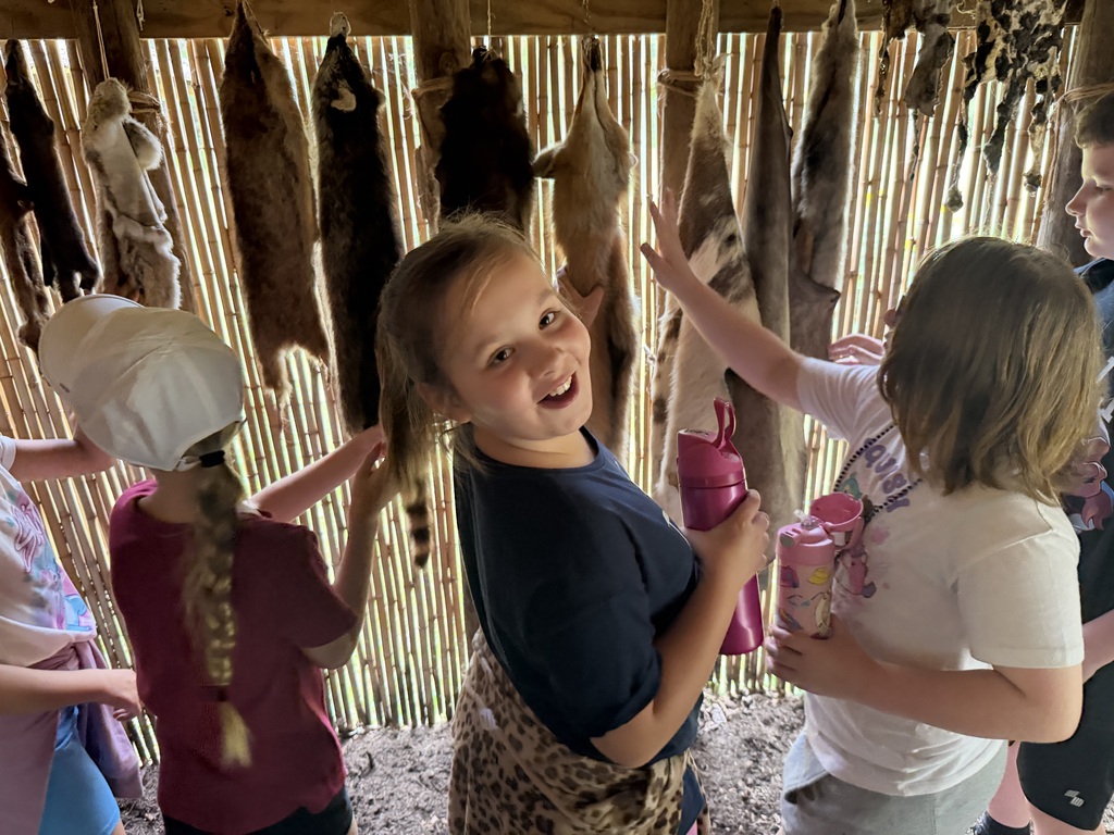 Smiling student learning about native americans and animal pelts.