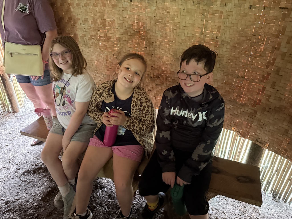 Smiling elementary students learning about native americans in an outdoor museum.
