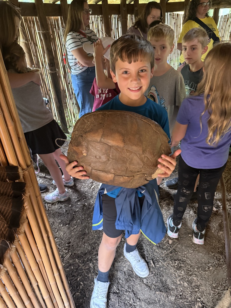 Smiling student in a native american home holding a wooden bowl.