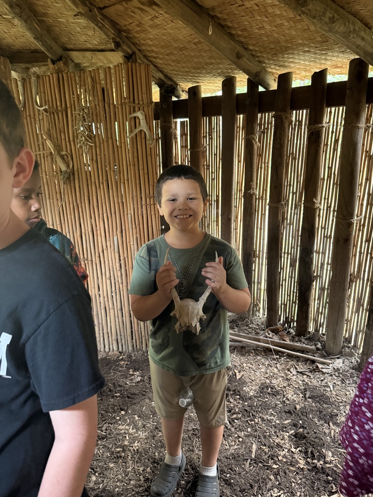 Smiling student in a native american home holding a skull with antlers.