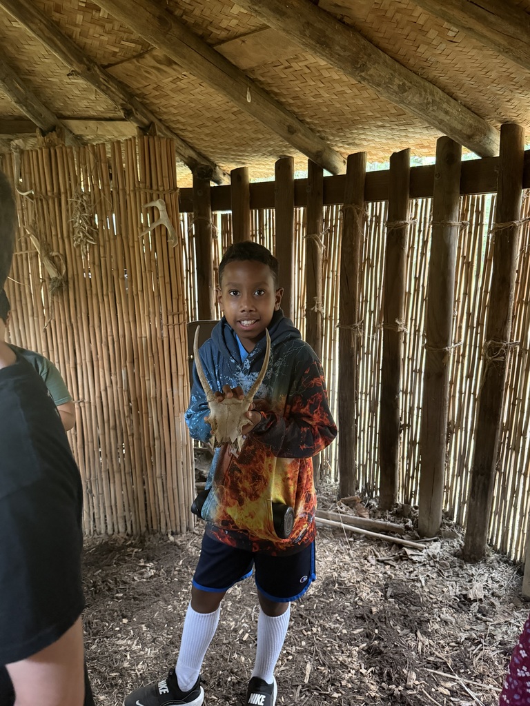 Smiling student in a native american home holding a skull with antlers.