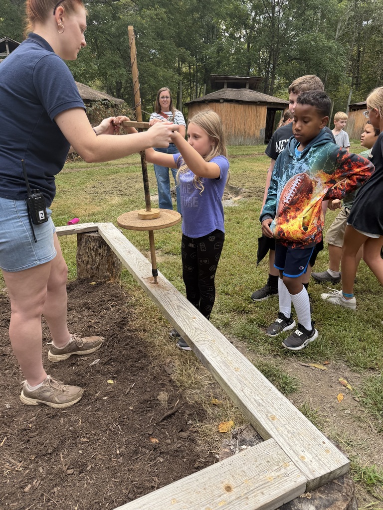 Elementary students learning about typical daily native american work near a garden. 