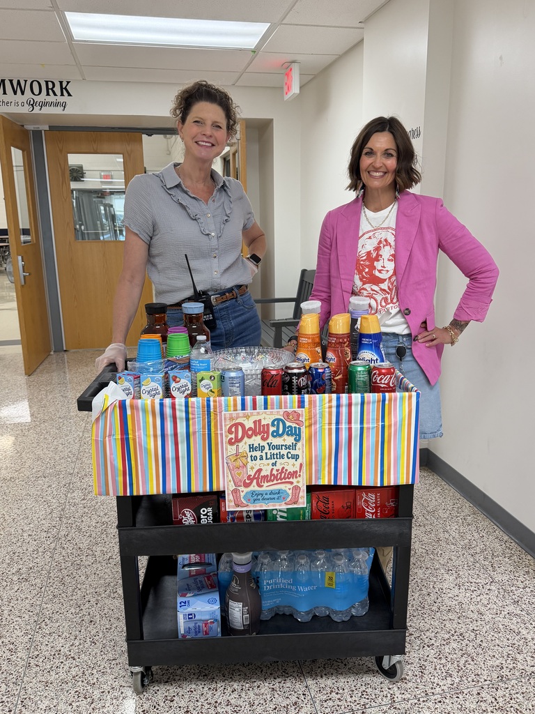 Two school administrators posing in front of a cart full of beverages, ready to roll around to classrooms to share with staff.