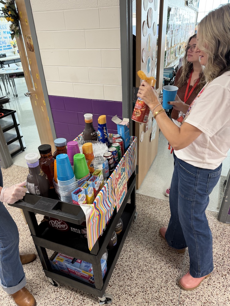 School administrator serving a teacher dressed in pink fun  beverages on a cart.