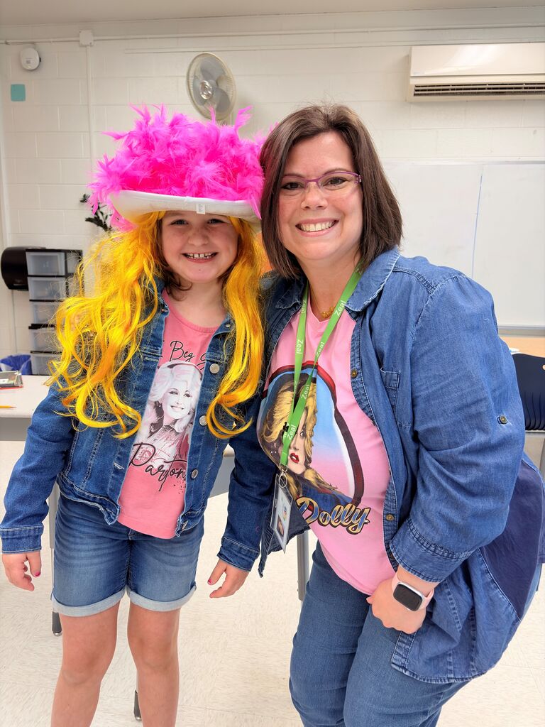Teacher and student in vibrant pink Dolly Partin stirts and denim jackets smiling.
