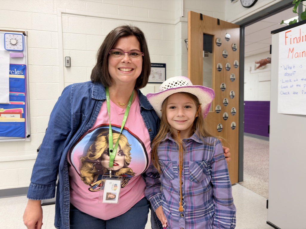 Teacher and student in vibrant pink and purple outfits smiling.