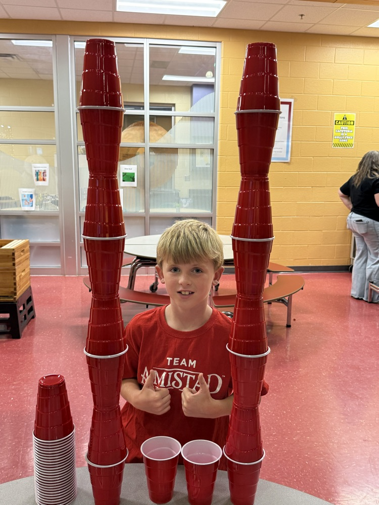 A young boy using a liquid pipette to mix colorful liquids in plastic cups.