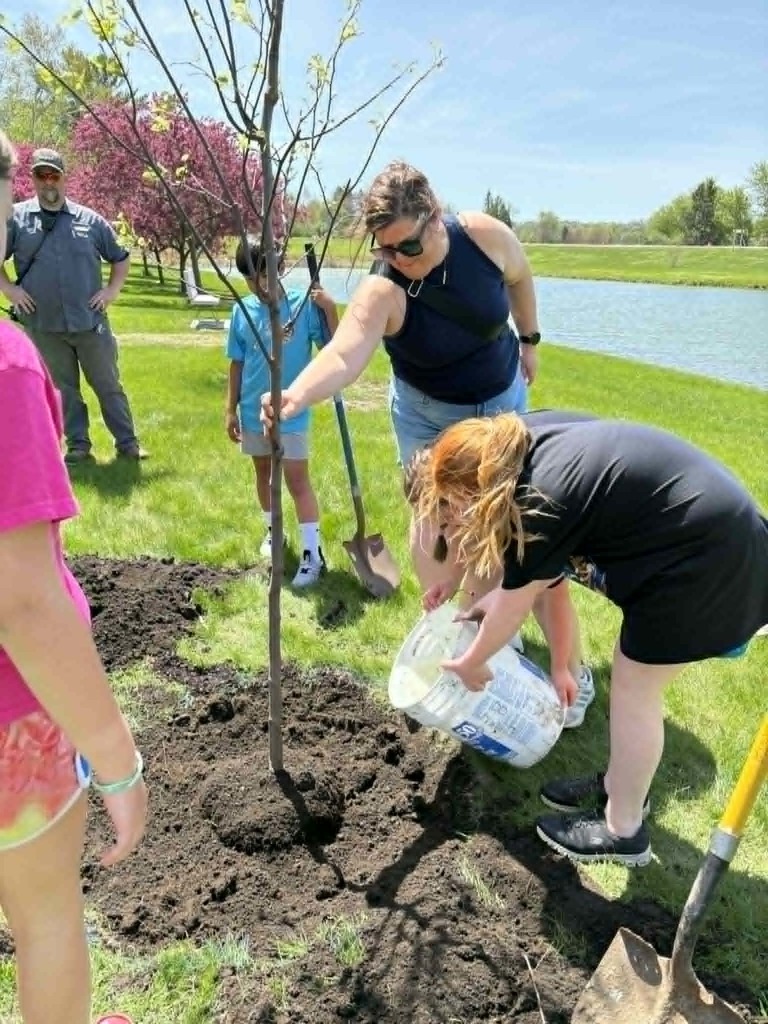 students and adult watering tree
