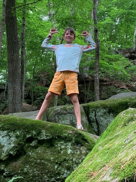 Middle school student flexing their muscles on a rock at Governor Dodge State Park