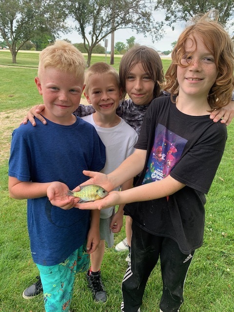 four elementary students holding a fish