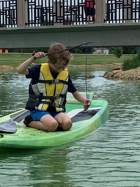 elementary student fishing on paddle board