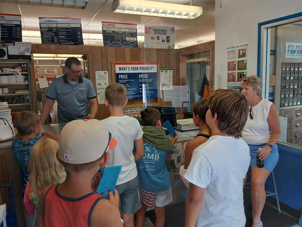 elementary students and teacher at the post office with the postmaster