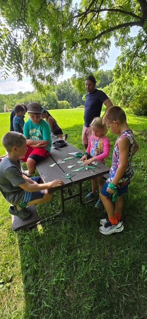 elementary students and teachers playging games at picnic table
