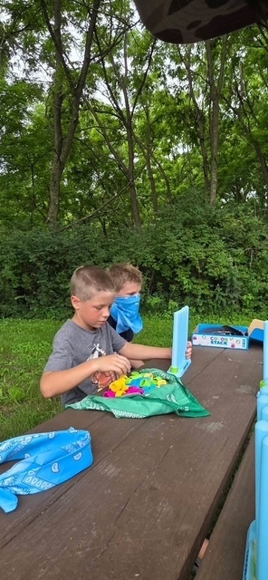 two elementary students creating crafts at picnic table