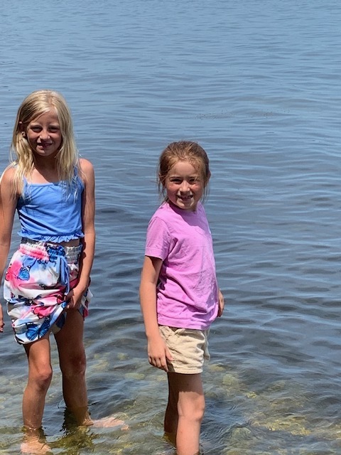 two elementary students wading in a lake