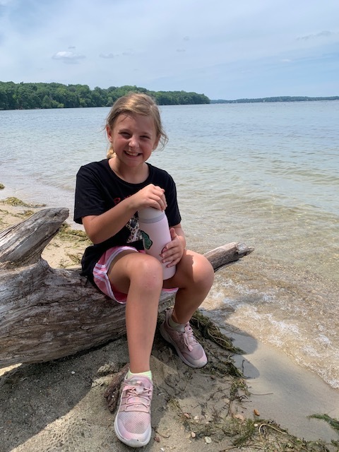 elementary student sitting by a lake