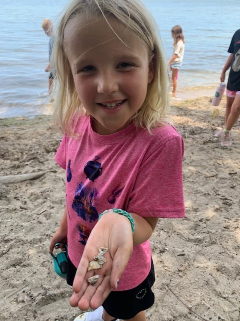 elementary student holding shells at a lake