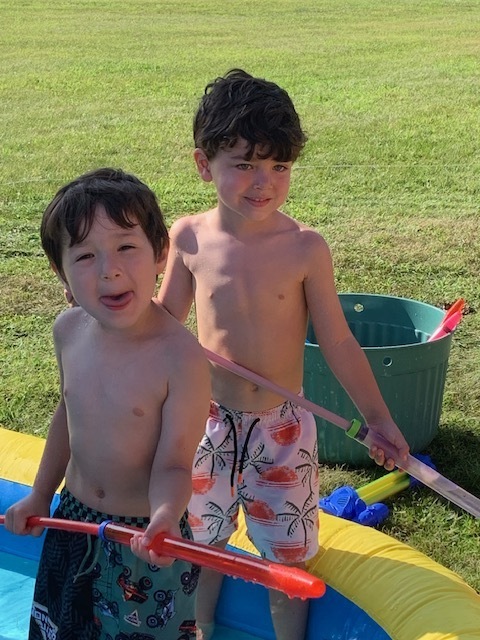 two elementary students in pool playing with pool toys