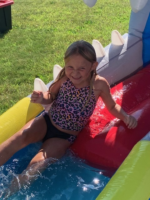 smiling elementary student going down blow up pool slide