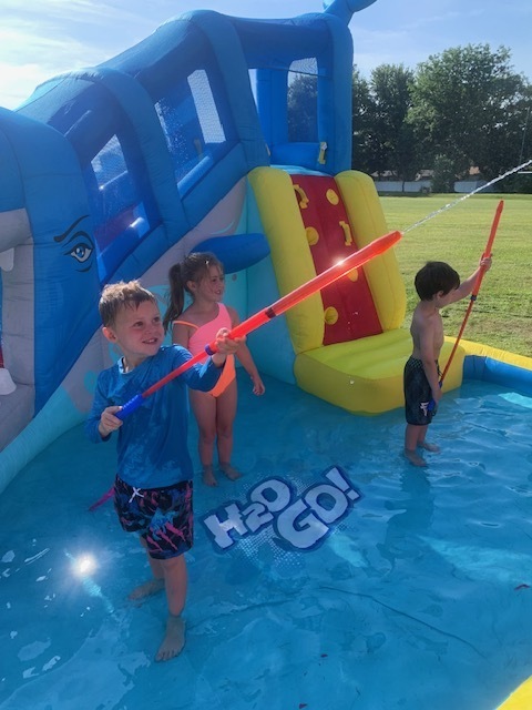 three elementary students in blow pool playing with pool toys
