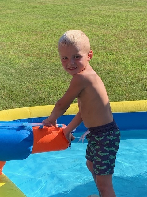 smiling elementary student playing in blow up pool