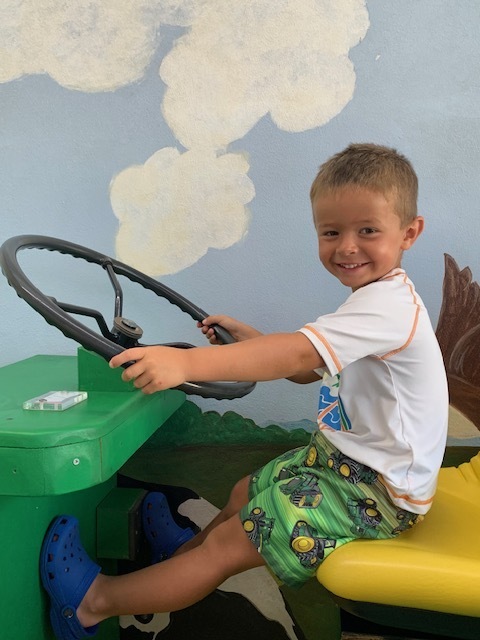smiling elementary student on toy tractor atBlack Earth Children's Museum