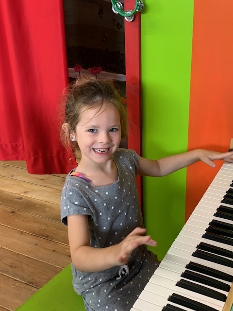 smiling student playing piano at Black Earth Children's Museum
