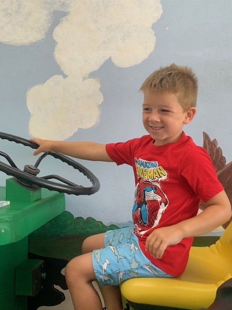 smiling elementary student on toy tractor at Black EarthChildren's Museum