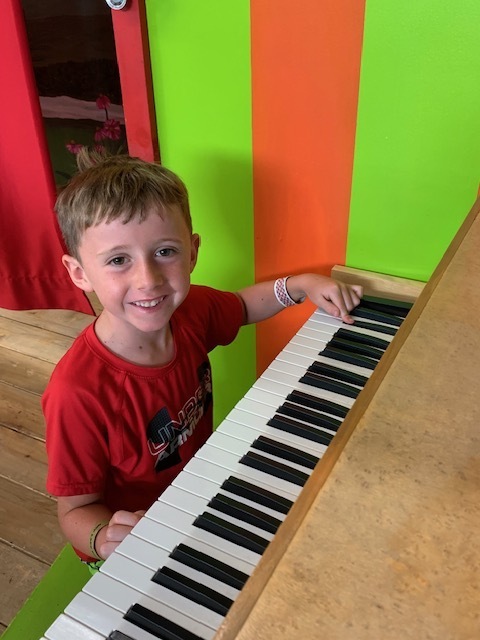 smiling student playing piano at Black Earth Children's Museum