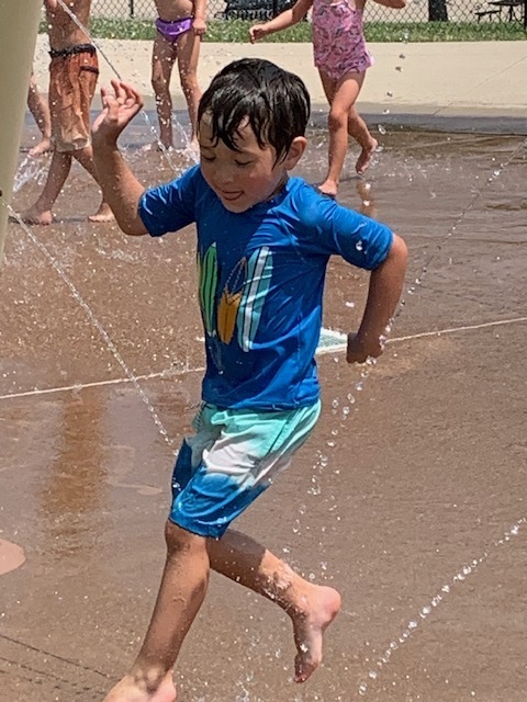 elementary student jumping through water at splash pad