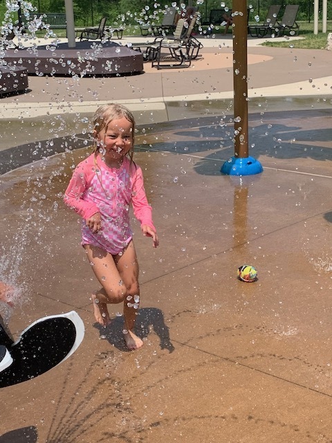 elementary student running through water at splash pad