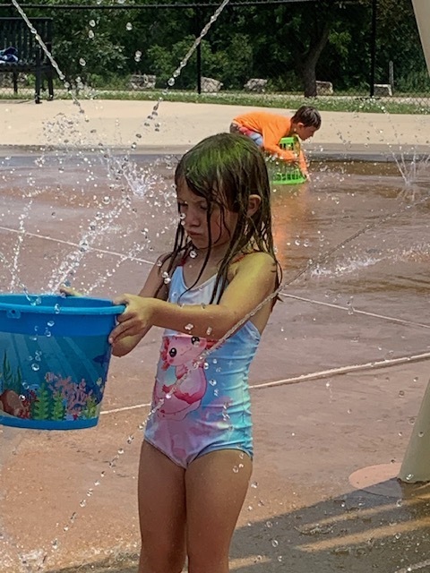 elementary student filling up bucket at splash pad