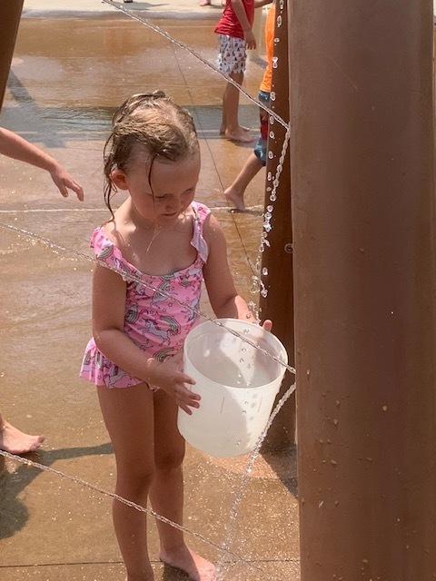 elementary student with bucket at splash pad