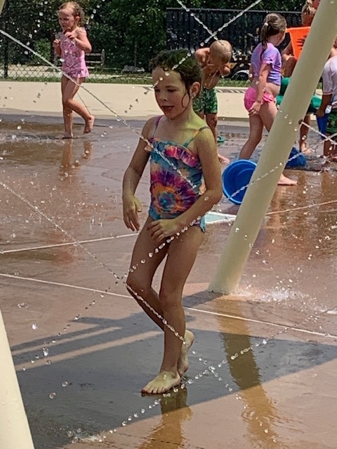 elementary student walking through water at splash pad
