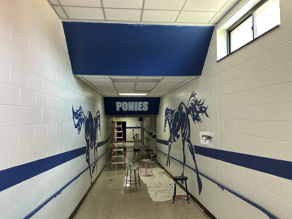 Kalyn Constantini standing beside the empty wall near the Tech Ed Shop before beginning her mural