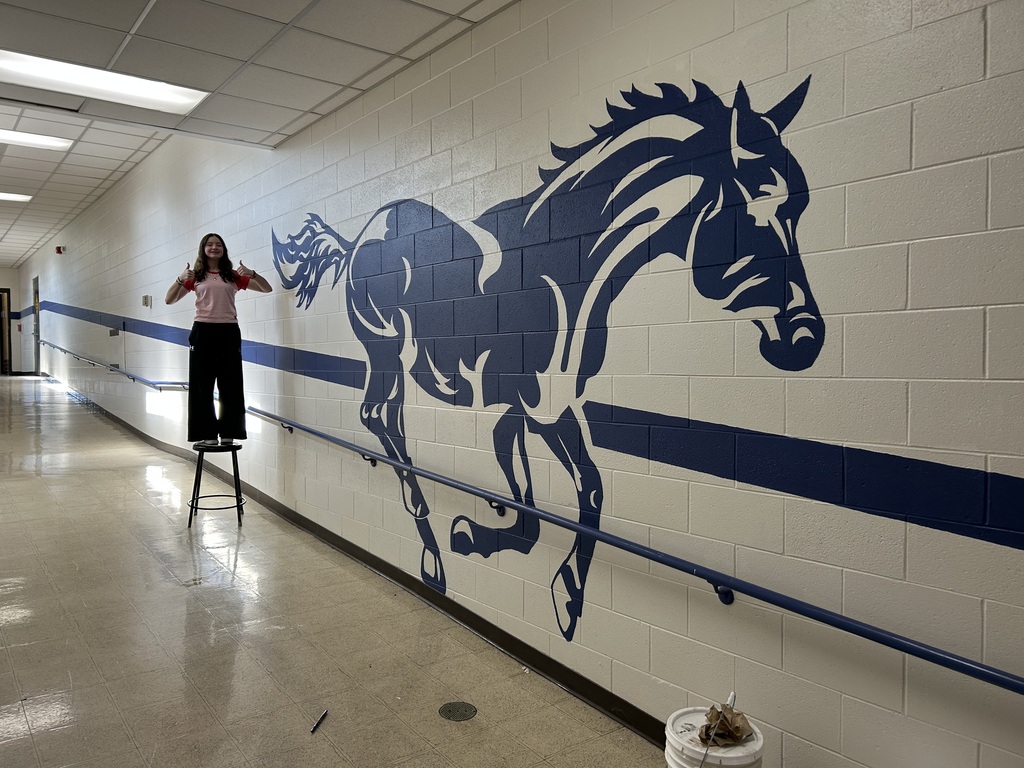 Kalyn Constantini standing beside the empty wall near the Tech Ed Shop before beginning her mural