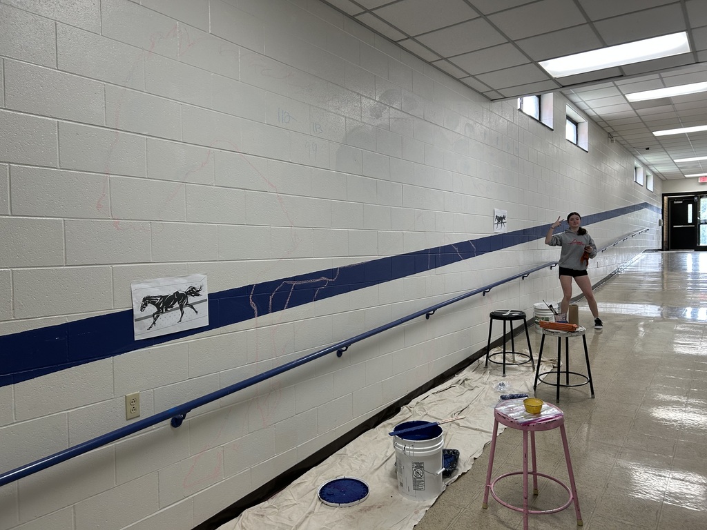 Kalyn Constantini standing beside the empty wall near the Tech Ed Shop before beginning her mural