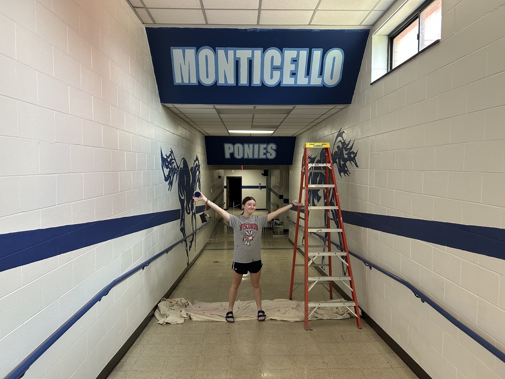 Kalyn Constantini standing beside the empty wall near the Tech Ed Shop before beginning her mural