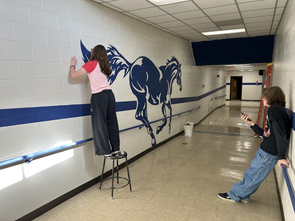 Kalyn Constantini painting the Pony mural on the wall along the ramp near the Tech Ed Shop