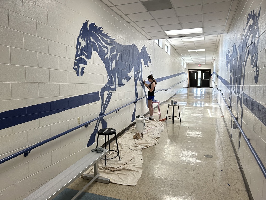Kalyn Constantini painting the Pony mural on the wall along the ramp near the Tech Ed Shop