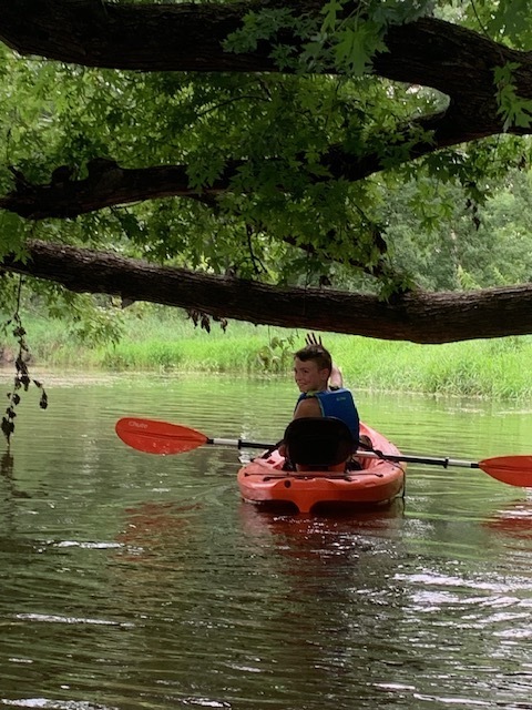 student waving while kayaking