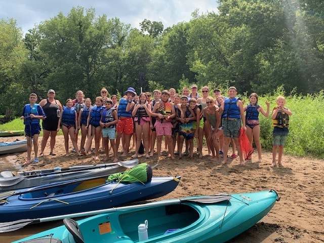 students and teachers on the beach ready to kayak