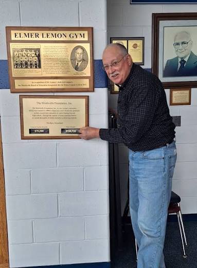 man pointing to scholarship amount on sign