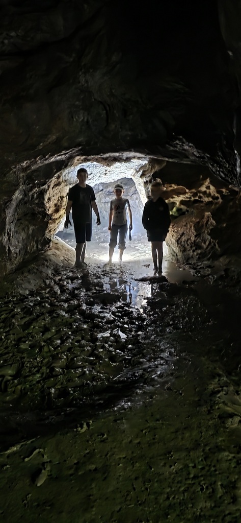 three students standing in the opening of Rainy Day Cave