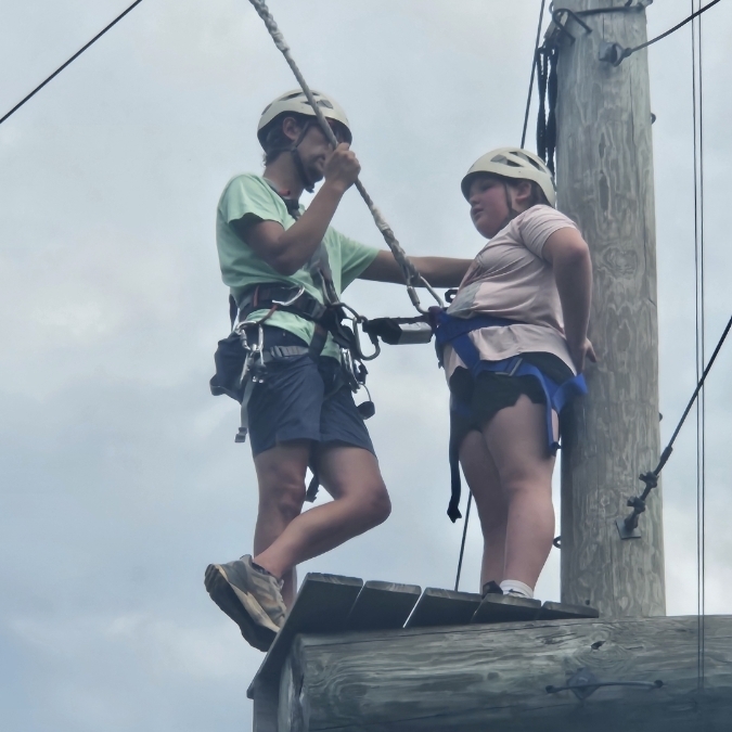 student and adult on high ropes course